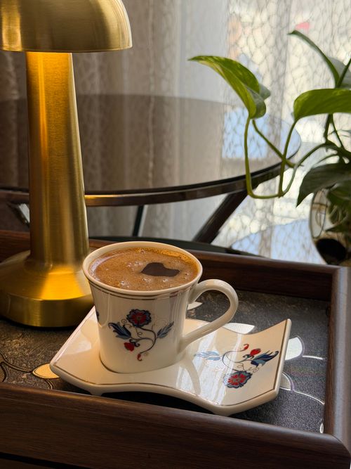 Free Stylish floral patterned coffee cup on a tray with soft lamp lighting. Perfect for cozy moments. Stock Photo