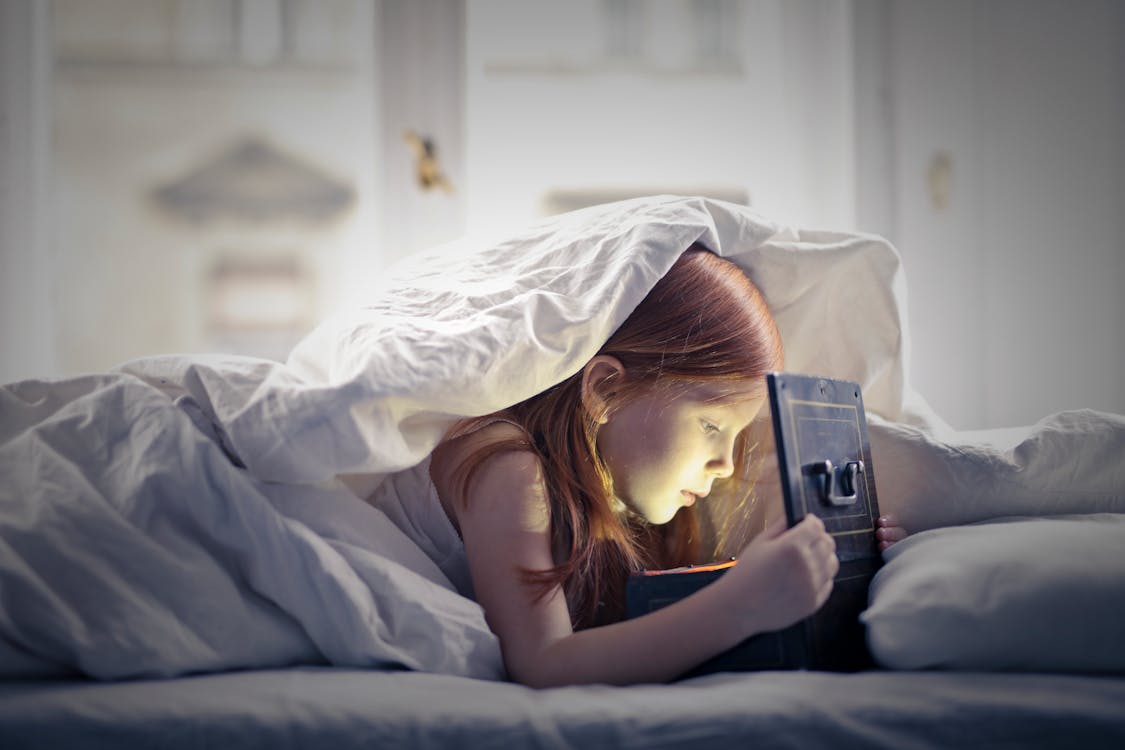 Free  Girl on Bed Looking At An Open Lighted Box Stock Photo