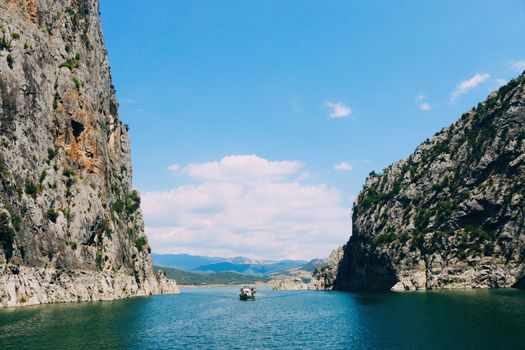 A boat traversing the serene waters of Kızılırmak River between stunning canyon cliffs in Samsun, Turkey.