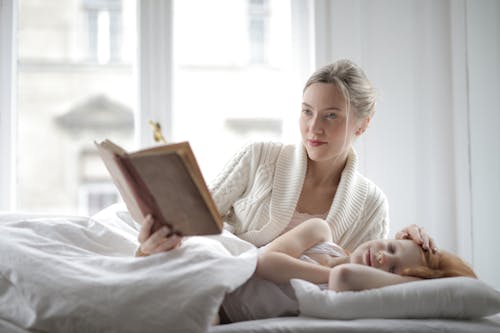 Free Mother Reading A Book To Her Daughter Stock Photo