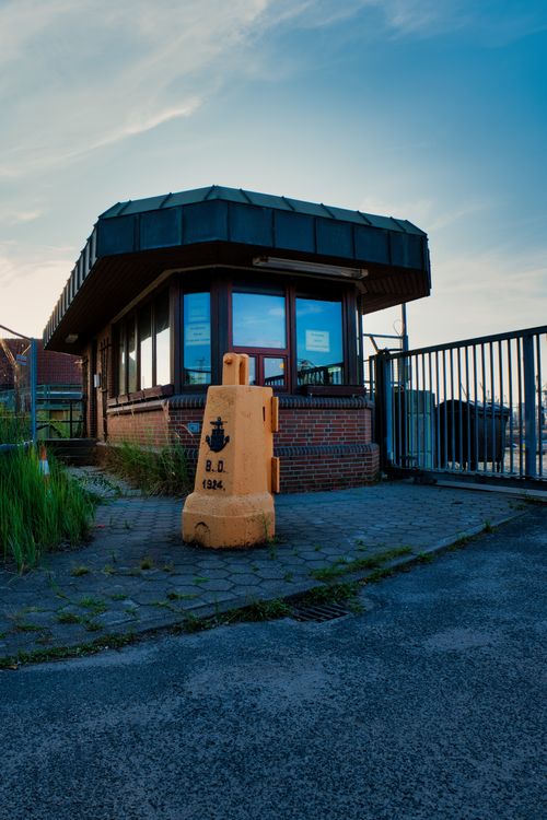 Free Brick guardhouse with a yellow bollard and sky backdrop at dusk. Stock Photo