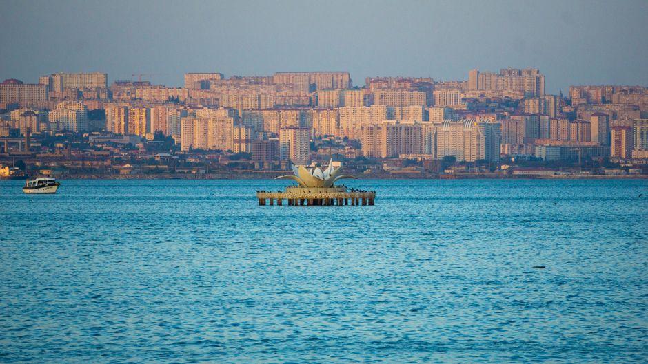 Stunning view of city skyline across the ocean with a small boat and platform at sea.