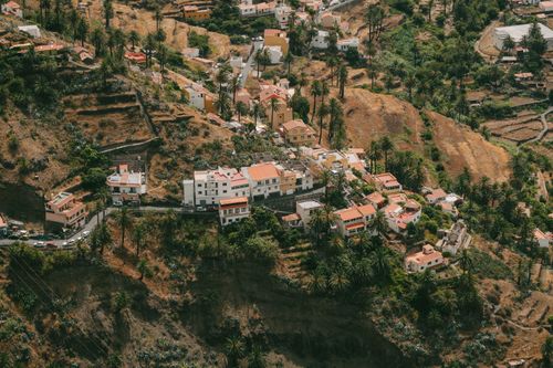 Free Scenic aerial view of a hillside village in Valle Gran Rey, La Gomera, dotted with palm trees and traditional houses. Stock Photo