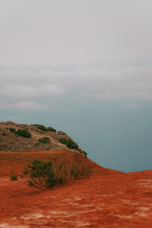 Free A tranquil view of red soil cliffs meeting low clouds over the ocean in Agulo, Canary Islands. Stock Photo