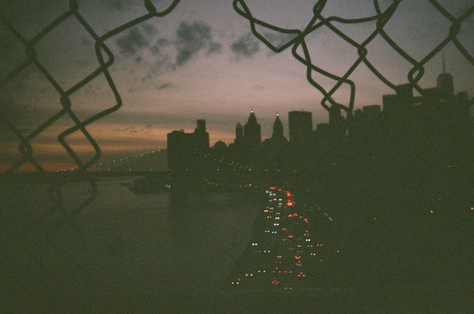 Dramatic twilight view of New York City skyline with city lights and waterfront.