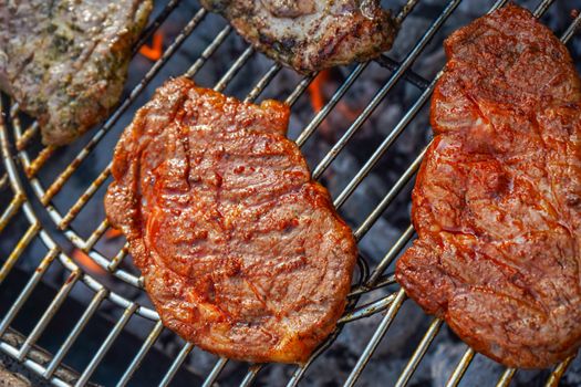 Juicy steaks sizzling on a barbecue grill, perfect for summer outdoor cooking.