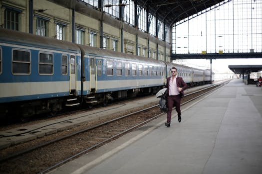 A businessman in a purple suit runs on a railway platform, rushing to catch a train during daylight.