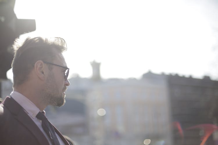 Stylish Handsome Man In Formal Outfit And Glasses On Street With Old Architecture