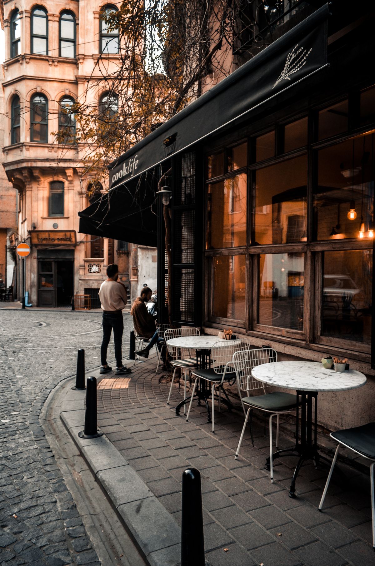 People at a cafe terrace on a cobbled street in Europe