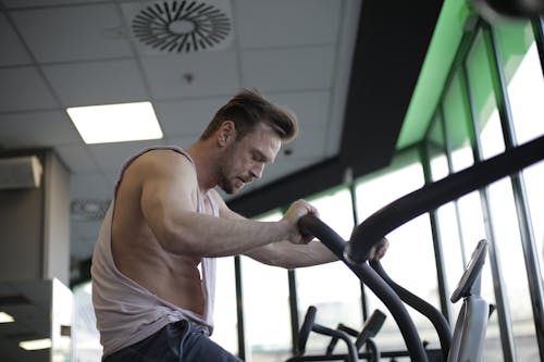 Free Strong sportsman using exercise bike during cardio workout in gym Stock Photo