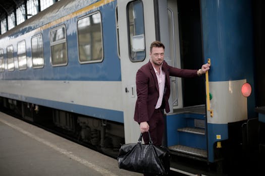 A well-dressed man in a burgundy suit boards a train holding his black travel bag.
