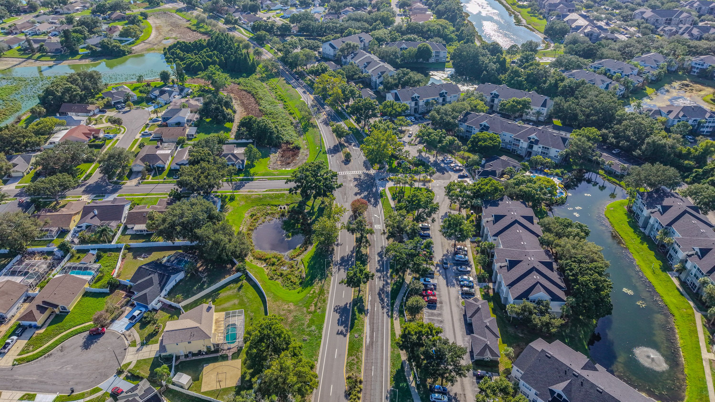 Detailed aerial view of a residential neighborhood in sunny Florida, showcasing houses, roads, and green areas.