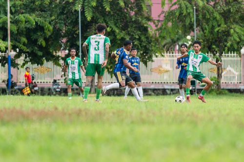 Free Amateur soccer players compete in a lively match outdoors on a grassy field with spectators in the background. Stock Photo