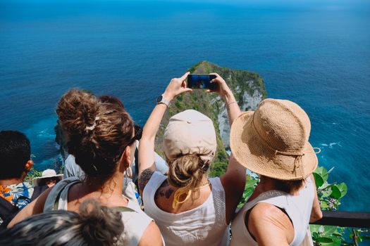 Adults capturing the stunning coastal views of Nusa Penida, Bali, Indonesia in the summer.