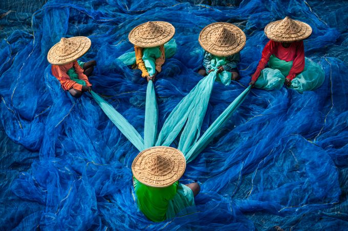 Overhead view of a crew spreading bright blue fishing nets together, photo by Monojit Dutta on Pexels