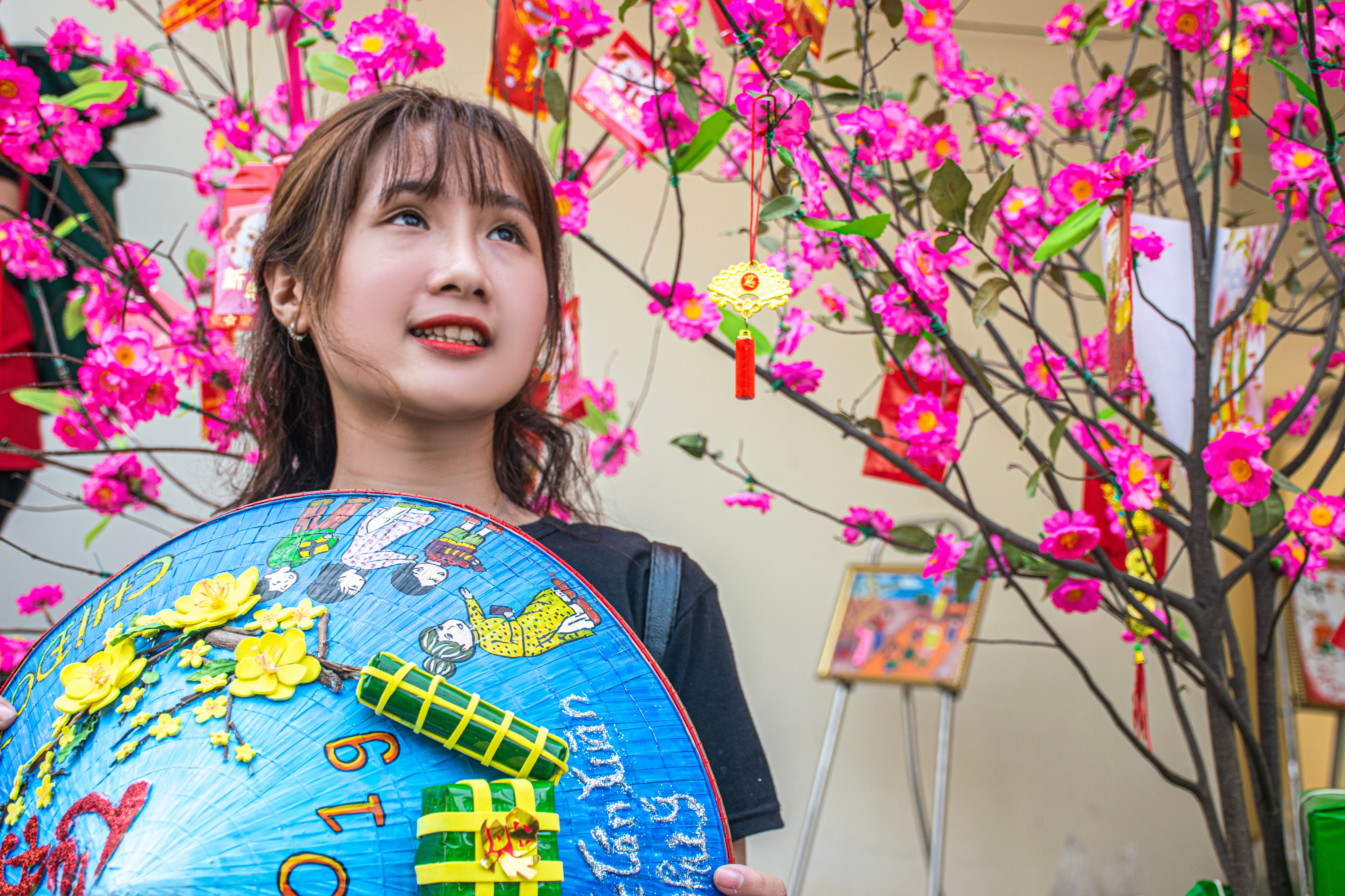 Young woman celebrating with cherry blossoms and festive decorations outdoors.
