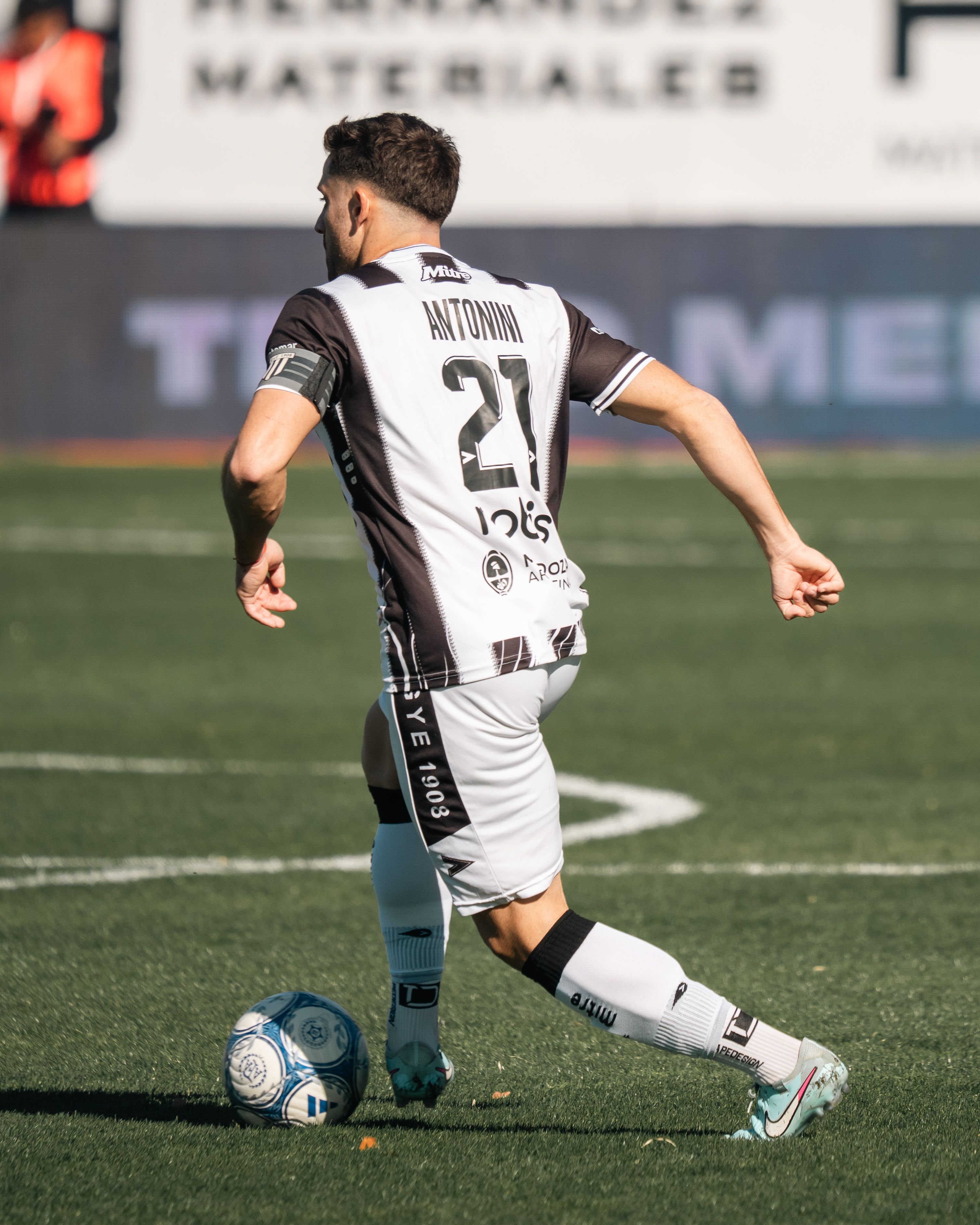 Soccer player dribbling a ball on an outdoor field during a match.