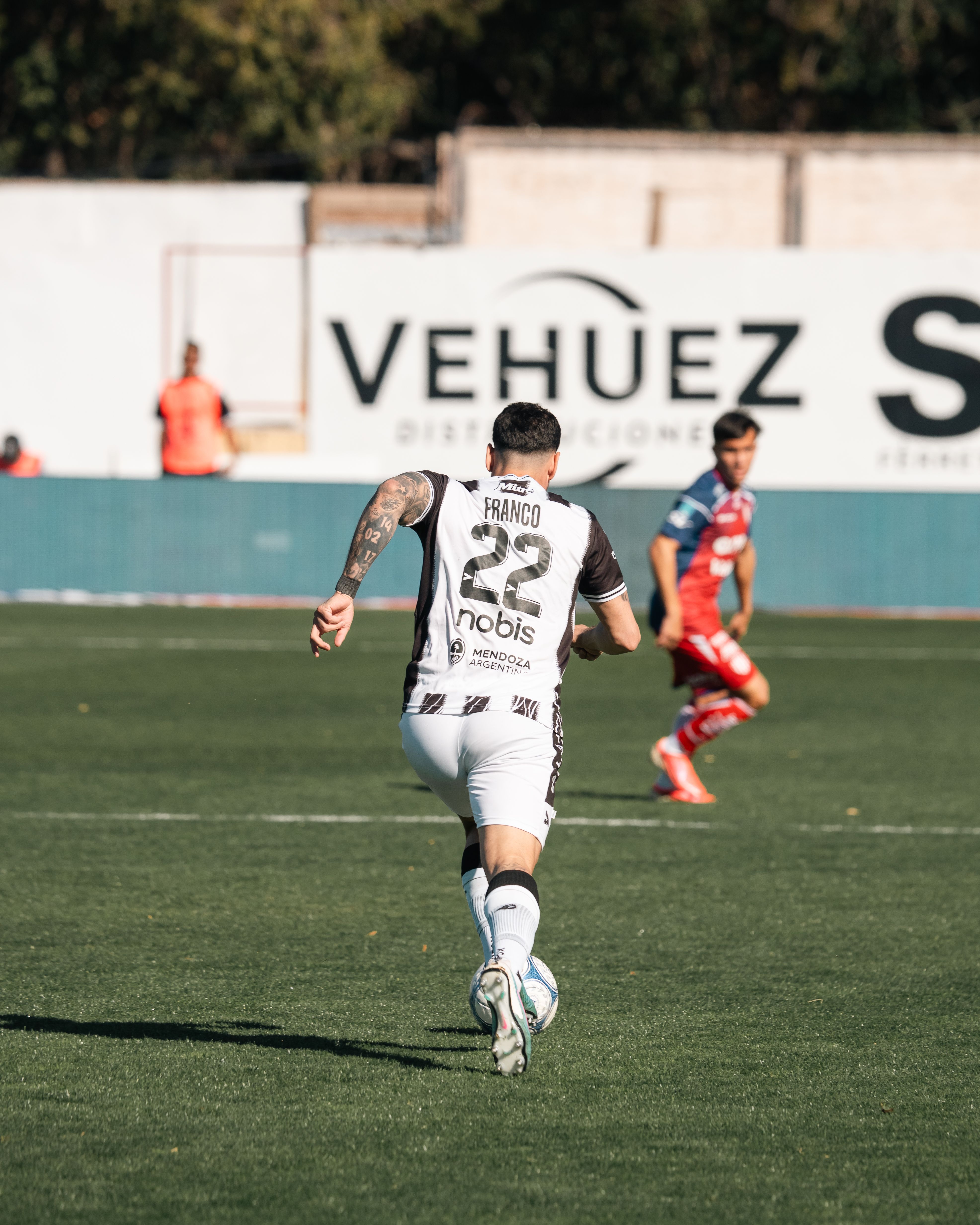 Action-packed soccer game with players in contrasting jerseys on a sunny day.