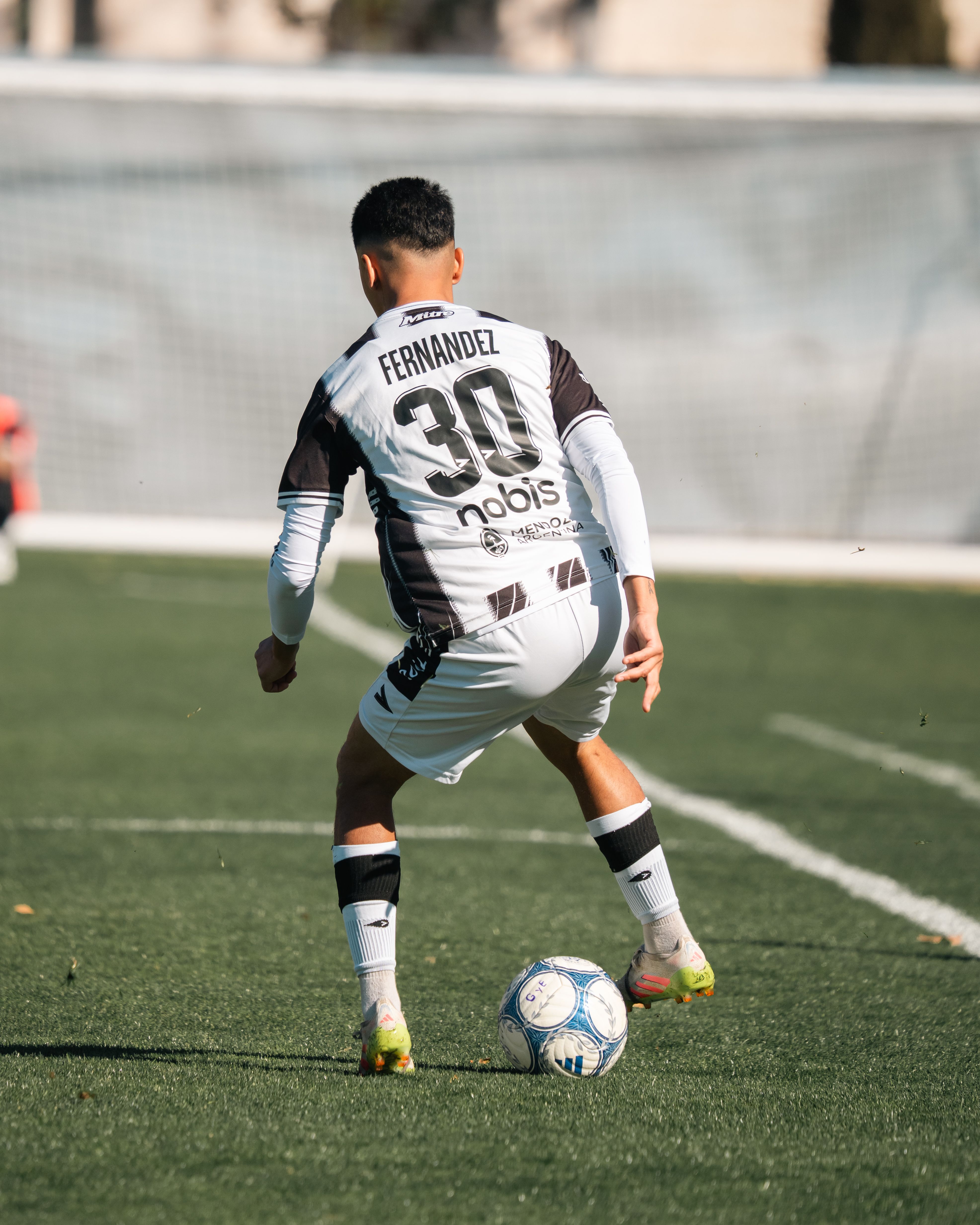 Soccer player dribbling on a sunny field during a match, showcasing athletic skills.