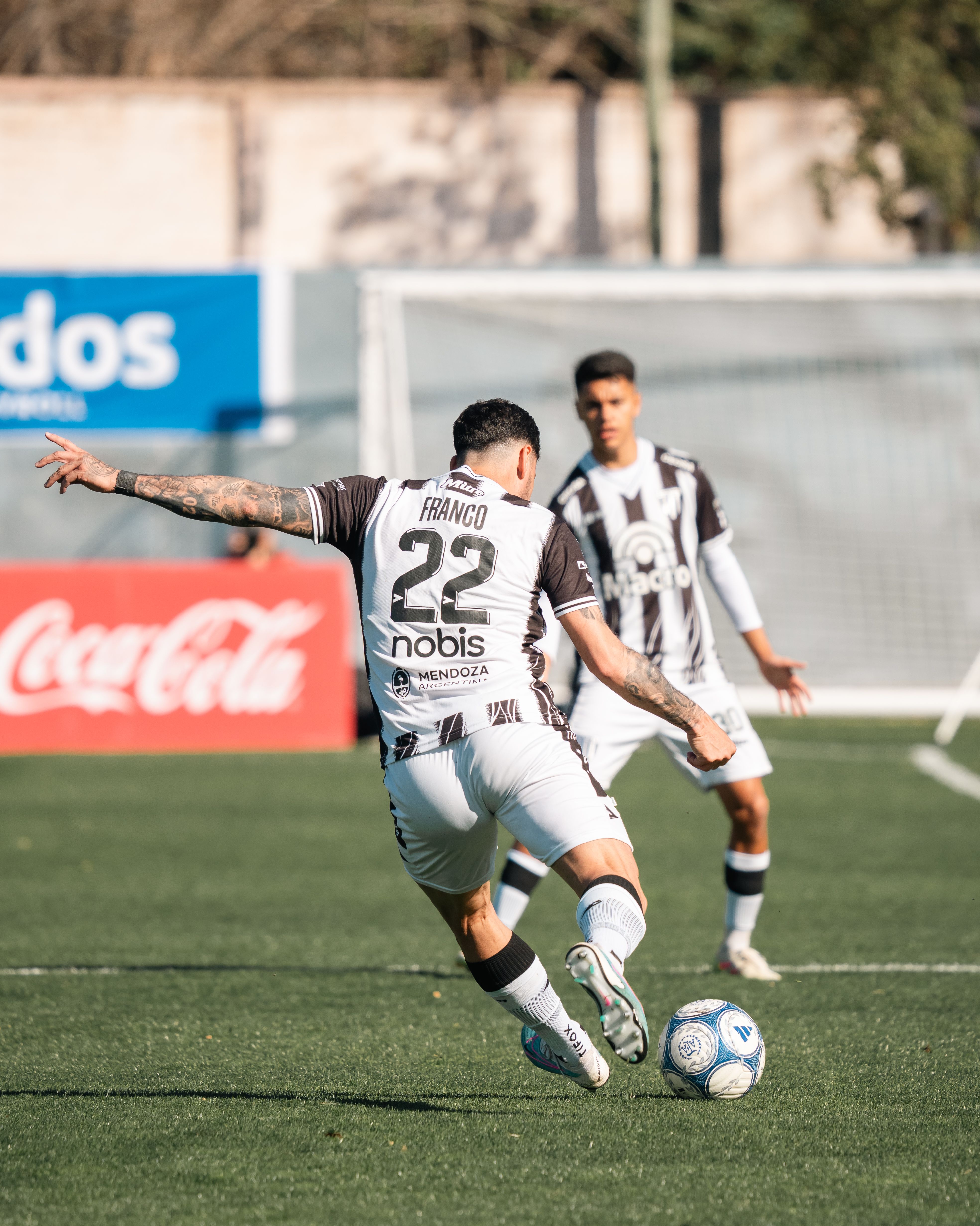 Action shot of soccer player kicking ball during a daytime match.