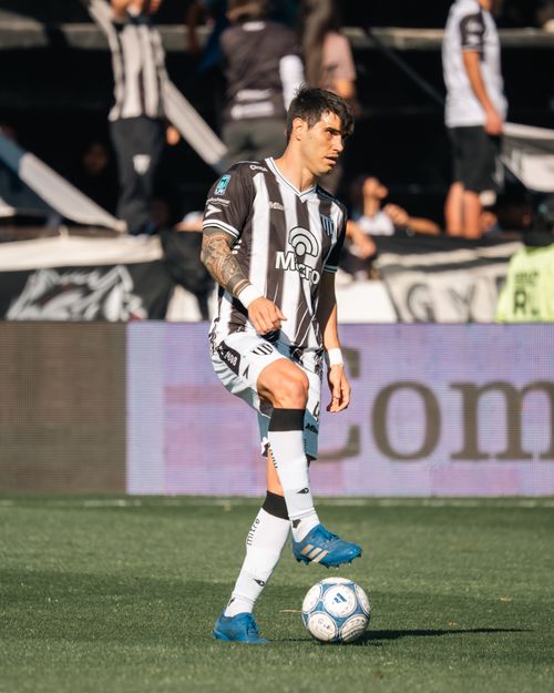 Free A male soccer player in action on the field wearing a striped jersey during a sunny day match. Stock Photo