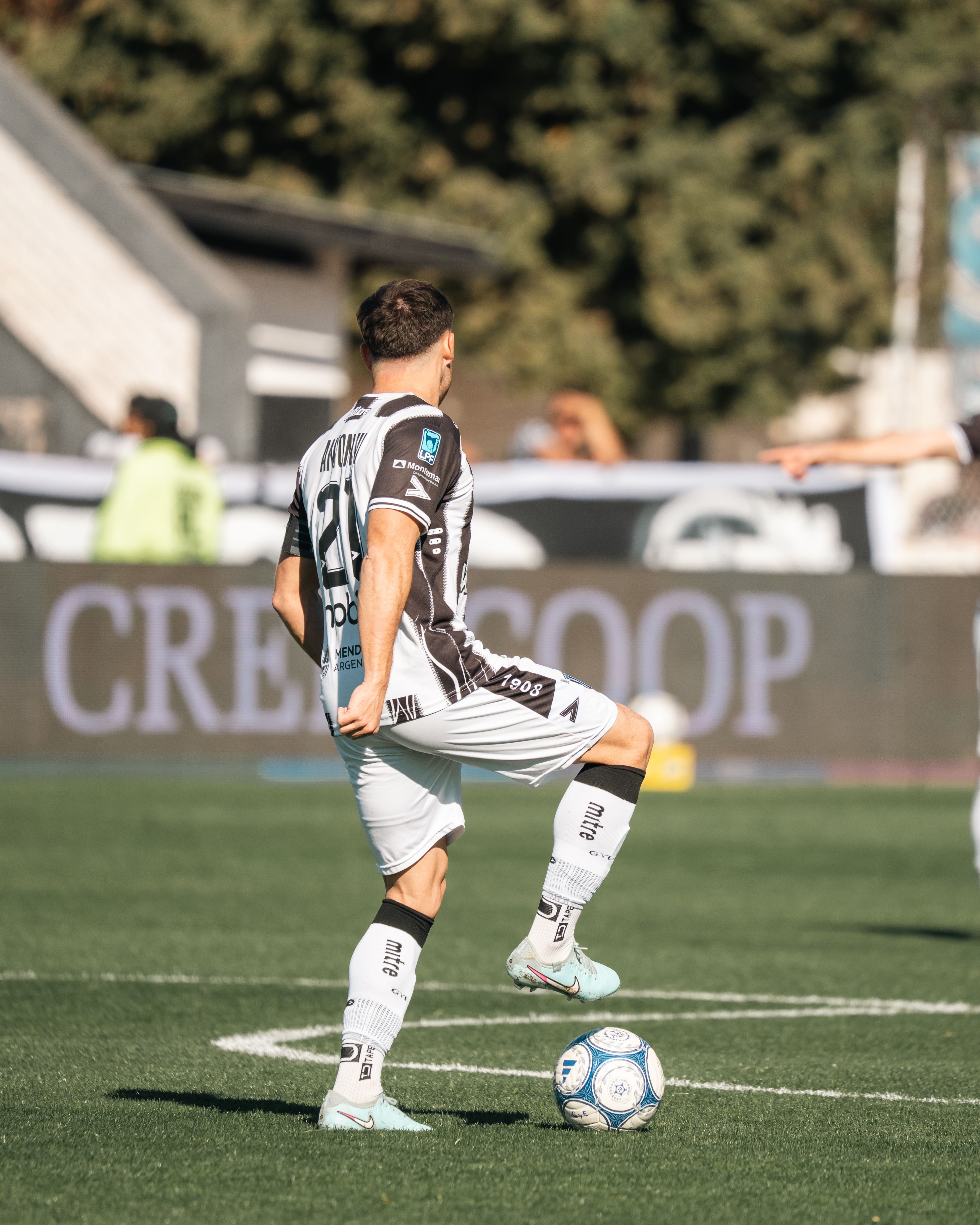 Soccer player in action on field during daytime match, featuring sporty uniform and dynamic pose.