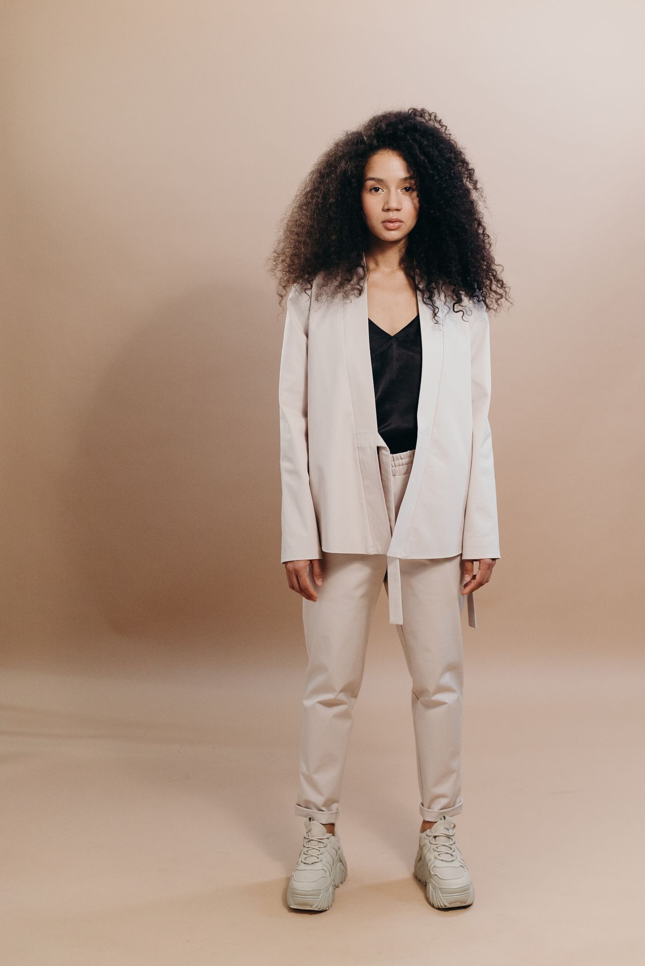 Woman wearing a beige blazer with matching trousers in a studio