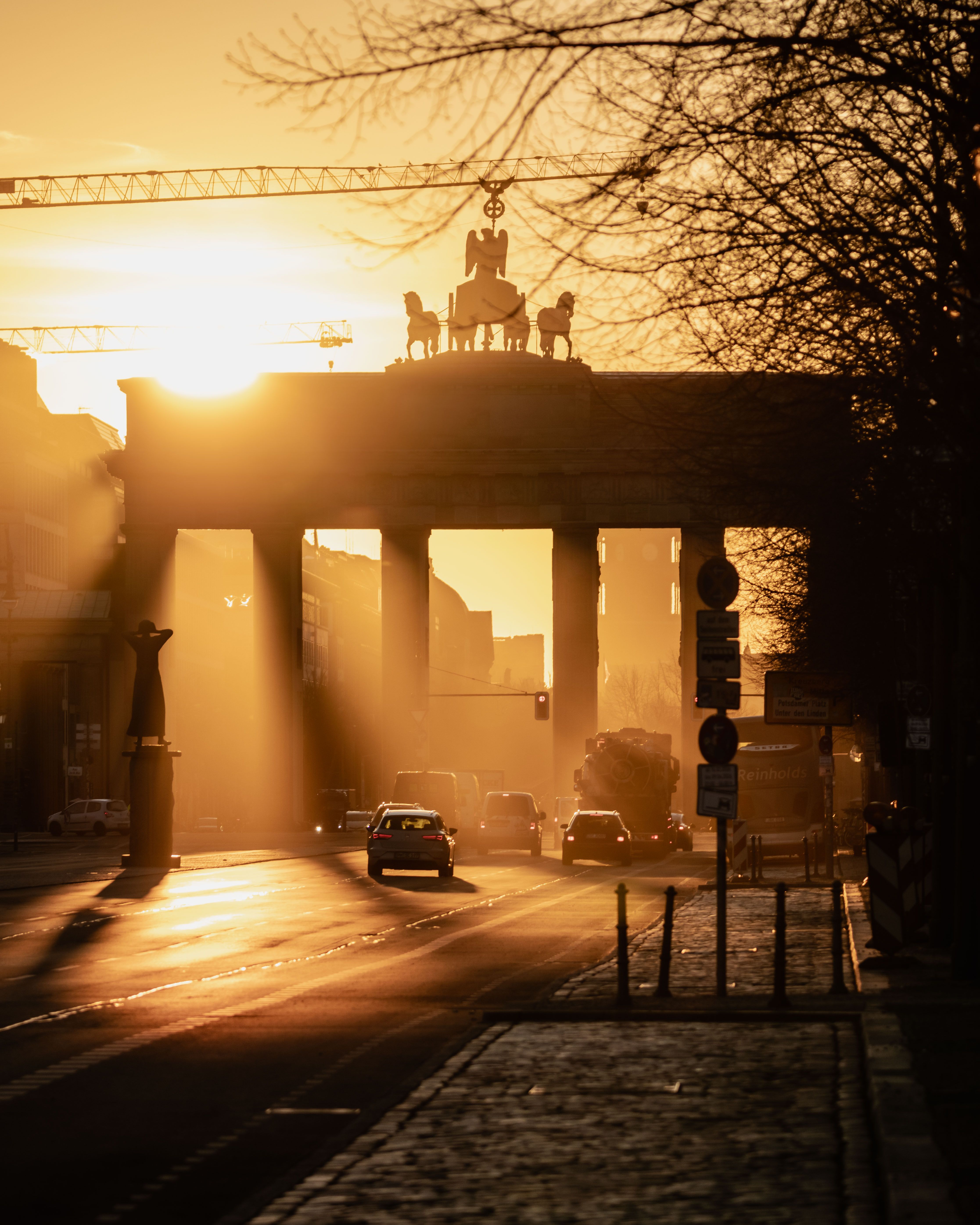 Brandenburg Gate silhouette at sunrise with golden light in Berlin, Germany.