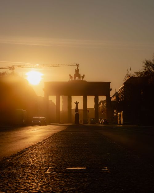 Free Dawn illuminates Brandenburg Gate in Berlin, casting a golden glow. Stock Photo