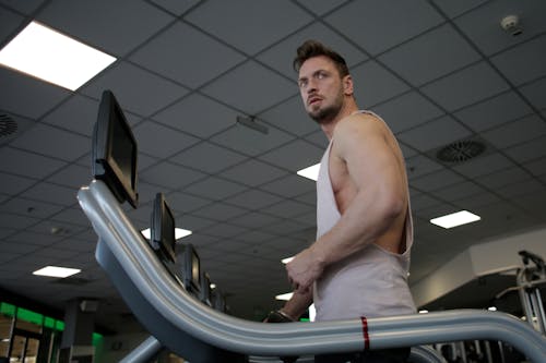 Strong sportsman using treadmill for cardio workout in gym