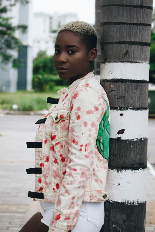 Free Portrait of an African woman with short hair standing against a tree wearing a trendy outfit. Stock Photo