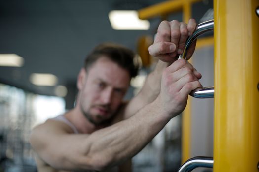Blurred view of a man intensely gripping gym equipment, showcasing fitness effort.