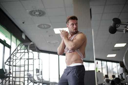 Muscular man adjusting shirt while exercising in a sleek, modern gym setting.