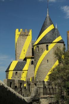 Stone castle adorned with striking yellow and black stripes under a clear blue sky.