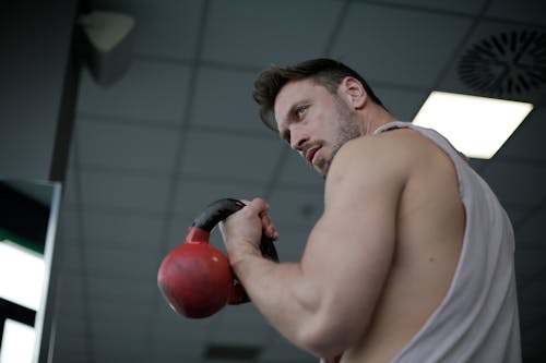 Strong confident sportsman during training with kettlebell in gym