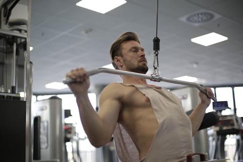 Topless Man in White Tank Top Holding Exercise Equipment