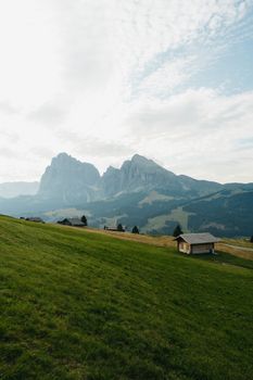 Peaceful alpine scenery featuring wooden cabins and majestic mountains under a cloudy sky.