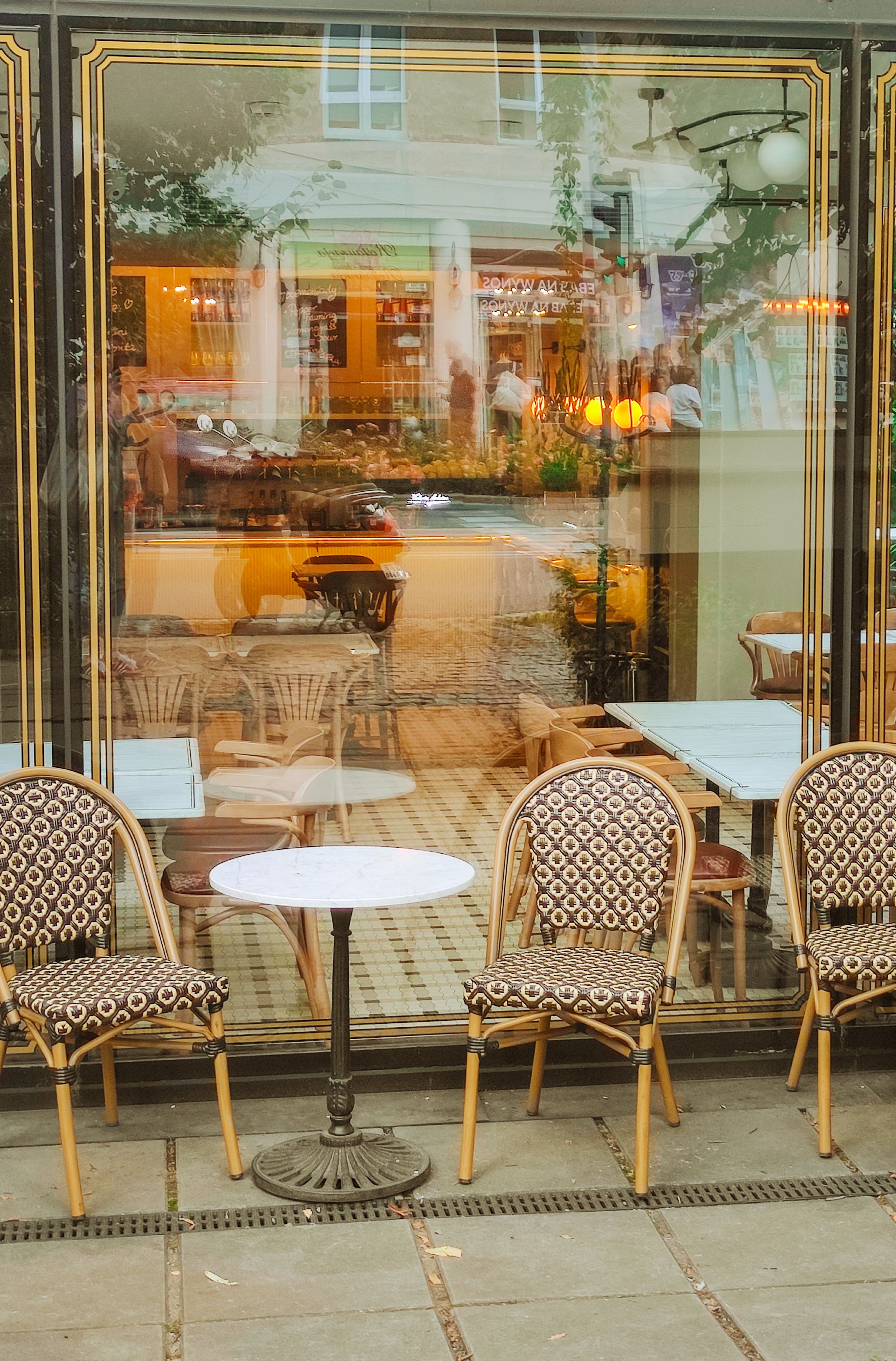 A cozy French café with distinctive rattan chairs and a warm inviting ambiance viewed from the street.