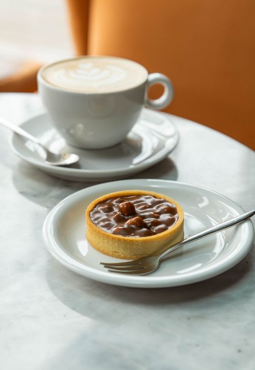 Free Enjoy a cozy French cafe experience with coffee and a sweet pastry. Stock Photo
