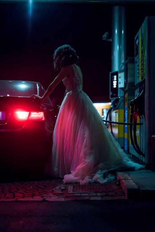 Woman in White Dress Fueling Car During Night