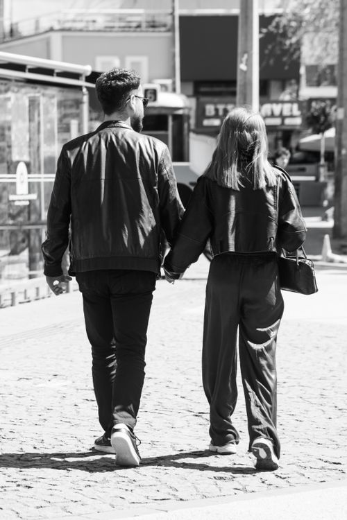 Free Black and white photo of a couple walking hand in hand in the city. Stock Photo