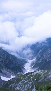 Stunning view of a mountain valley with clouds hovering above, creating a dramatic and serene landscape.