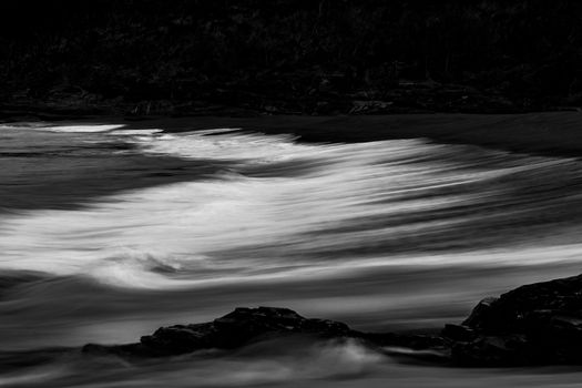 Captivating black and white photo of waves crashing on rocks at South Durras Beach, Australia.
