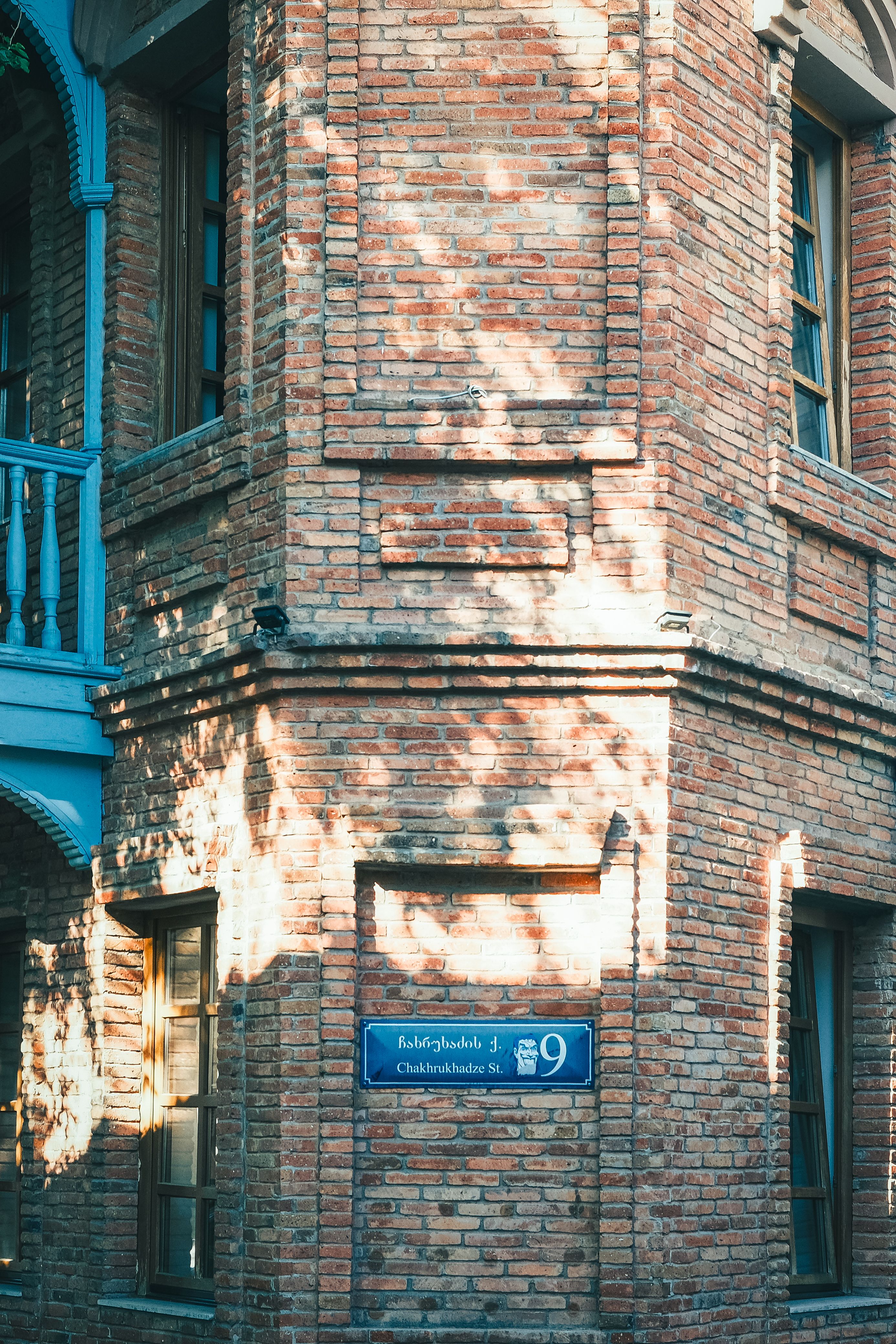 Sunlight casts shadows on a historic brick building at Chakhrukhadze Street, highlighting its architectural charm.
