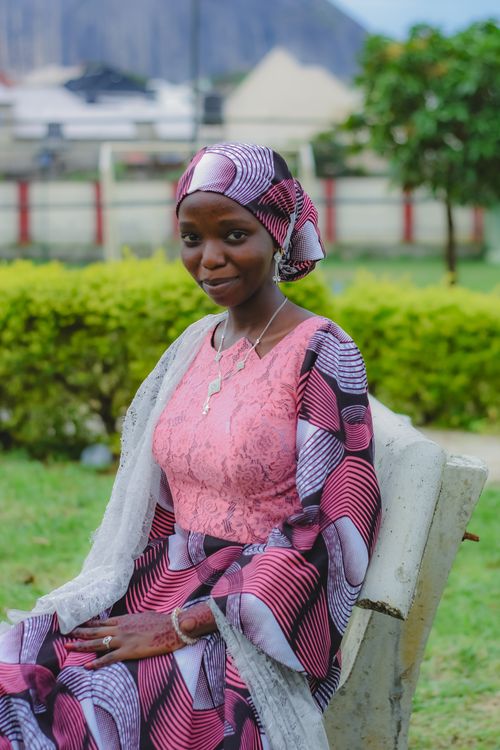 Free A woman in colorful traditional attire seated outdoors in Abuja, Nigeria. Stock Photo