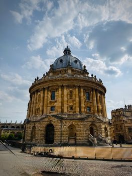 The historic Radcliffe Camera basking in sunshine under a picturesque sky in Oxford, England.