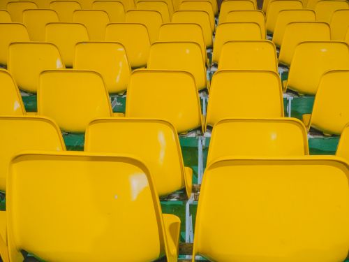 Free Rows of bright yellow stadium seats creating a vivid and symmetrical pattern in an outdoor setting. Stock Photo