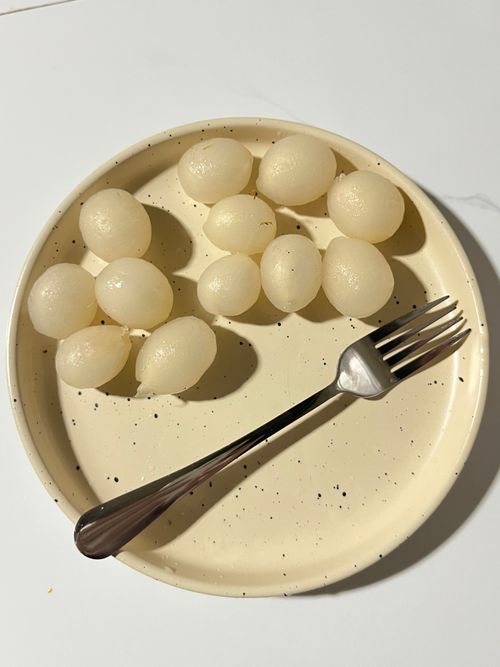 Free A simple, minimalist composition featuring lychee fruits on a round plate with a fork, captured in natural light. Stock Photo