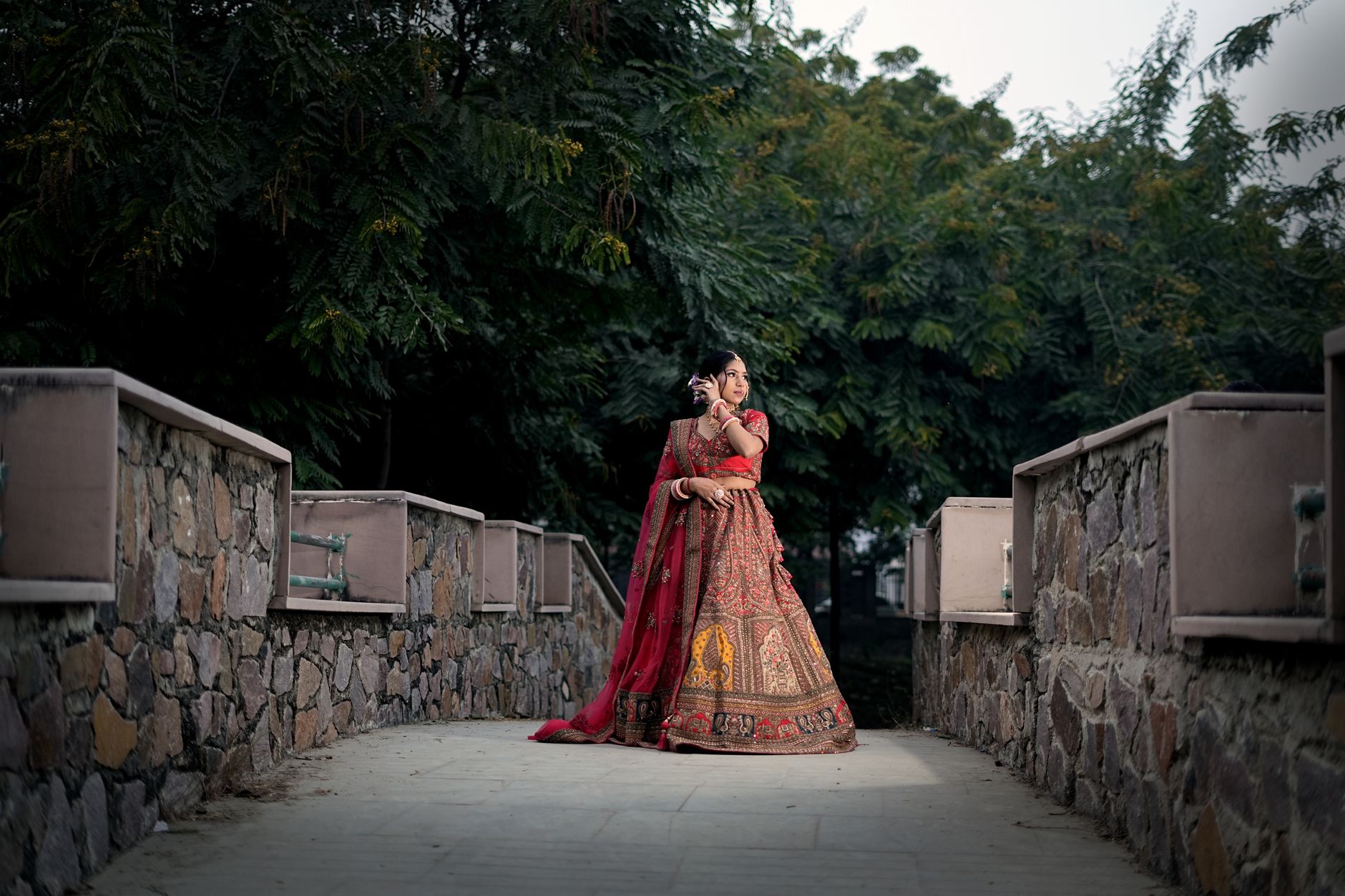 Standar Pelayanan Profesional dalam Menyediakan Paket Wedding Impian Anda 3 Beautiful Asian bride in traditional attire posing on a rustic stone bridge in Lucknow, India.