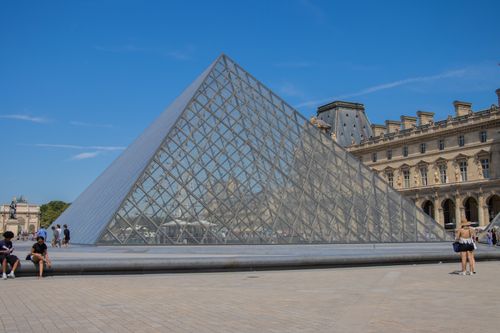 Free Iconic Louvre Pyramid under a clear blue sky in Paris, France. Stock Photo